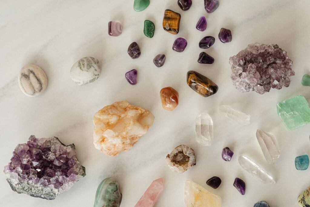 Colección de cuarzos y piedras de colores sobre superficie de madera, incluyendo cuarzo rosa, amatista y turmalina negra
