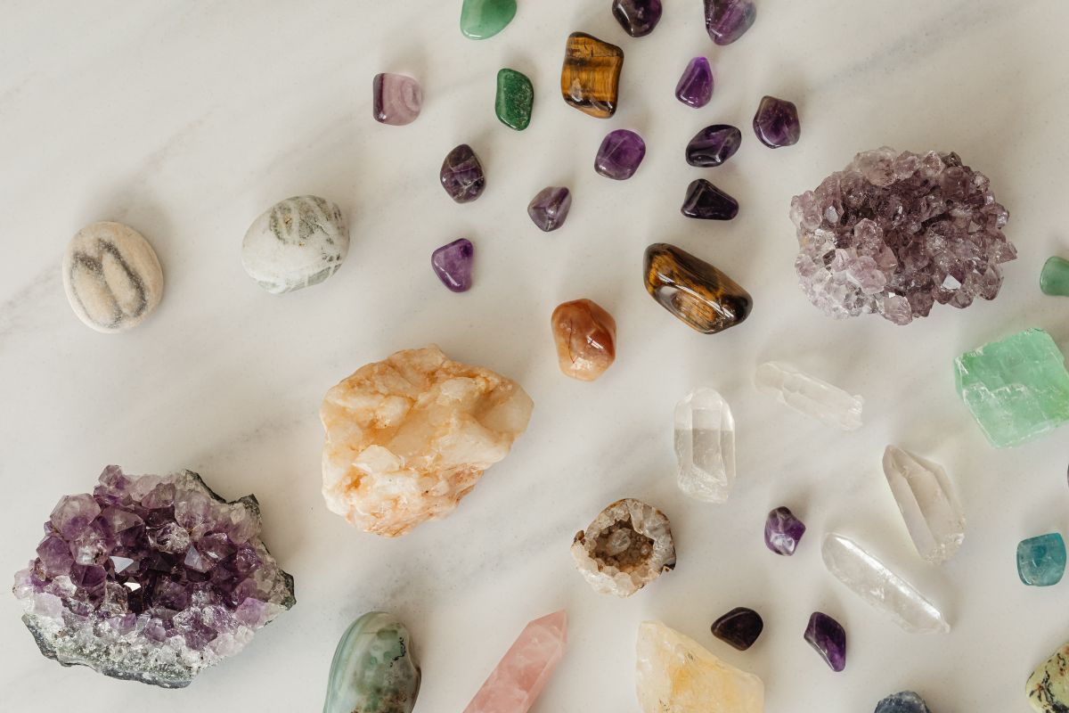 Colección de cuarzos y piedras de colores sobre superficie de madera, incluyendo cuarzo rosa, amatista y turmalina negra